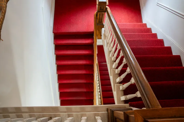 Red-carpeted staircase and wooden banister